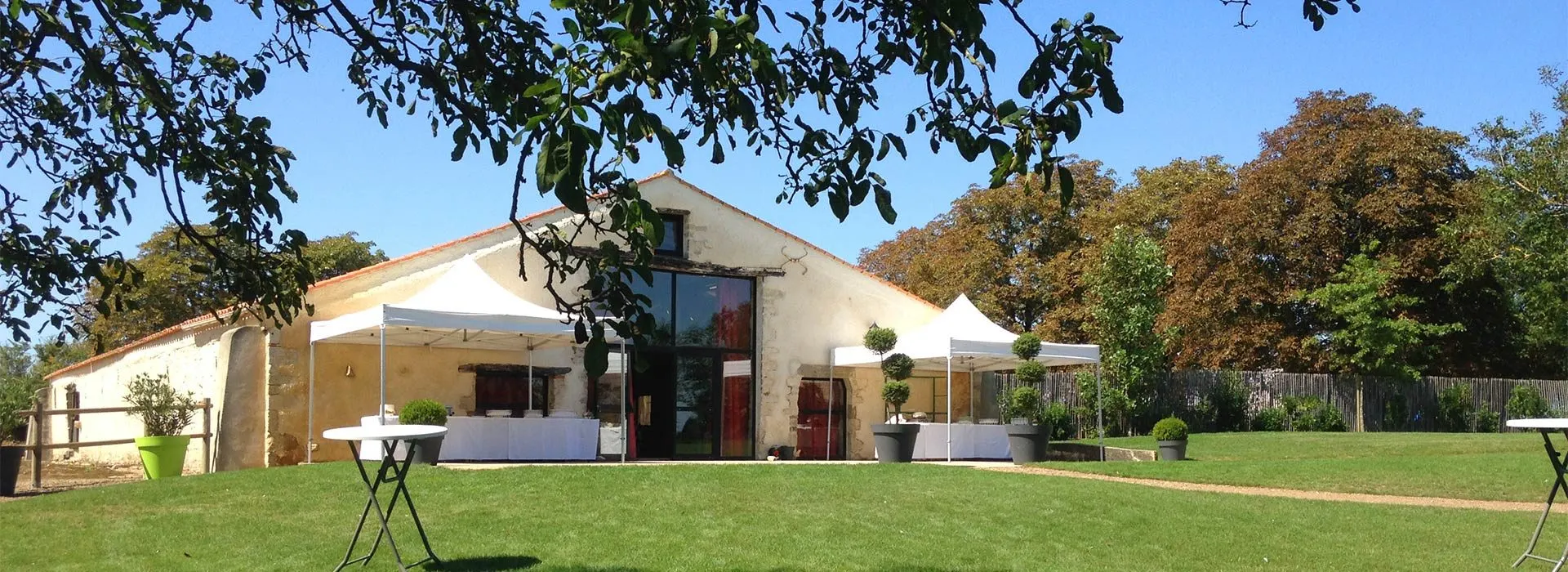 La façade de la Grange du Prieuré, ses tonnelles blanches et sa pelouse